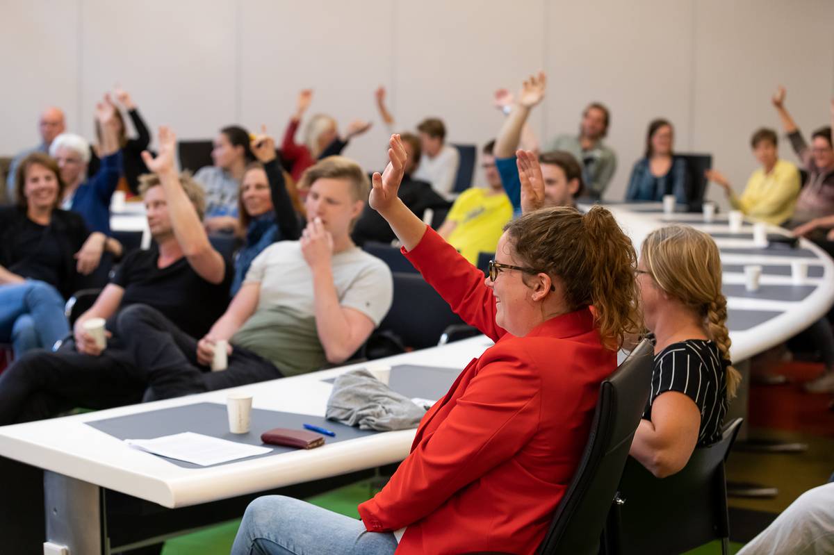 deelnemers in de zaal steken hand op deelnemers in de zaal steken hand op